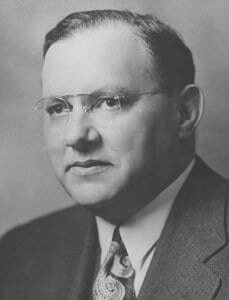 Portrait of a distinguished man wearing glasses and a suit, representing historical figures at The History Museum.