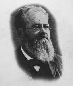 A historical black-and-white portrait of a bearded man with glasses.