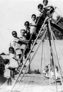 Children playing on a vintage playground slide, capturing historical moments of childhood recreation.