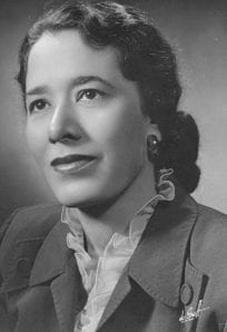 Black and white portrait of a woman, dressed in vintage attire, showcasing historical fashion.