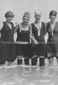 Women in early 20th-century bathing costumes at the lake, representing historical fashion and leisure activities.