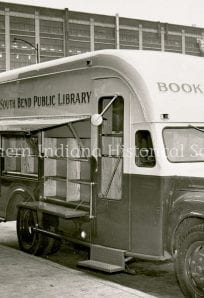 Bookmobile serving as South Bend Public Library outreach vehicle in front of a modern building.