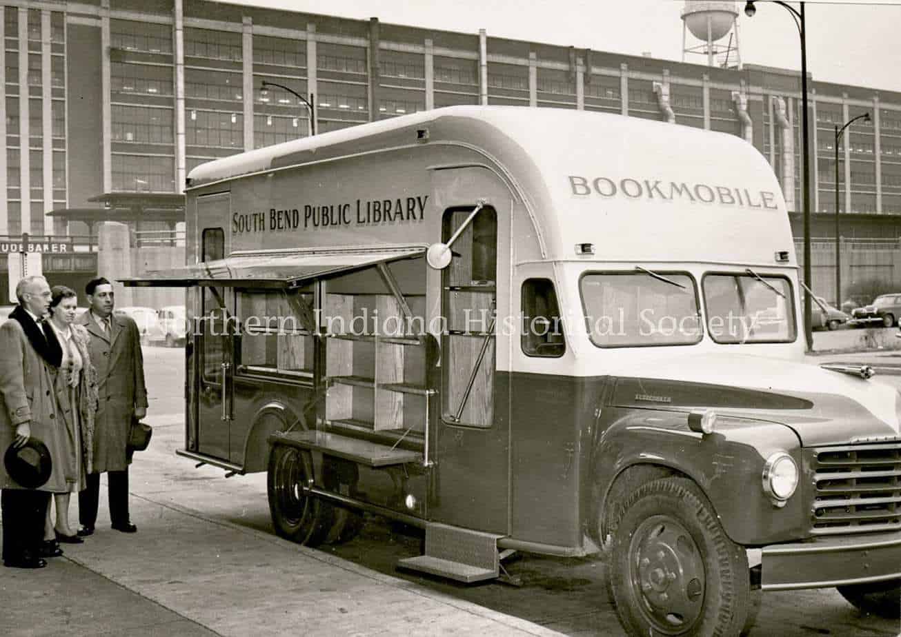 Bookmobile serving as South Bend Public Library outreach vehicle in front of a modern building.