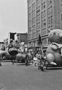 Colorful parade floats featuring cartoon characters on city street during celebration.