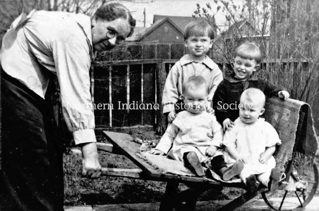 Childhood outdoor playing with woman and kids in backyard, vintage black and white photo.