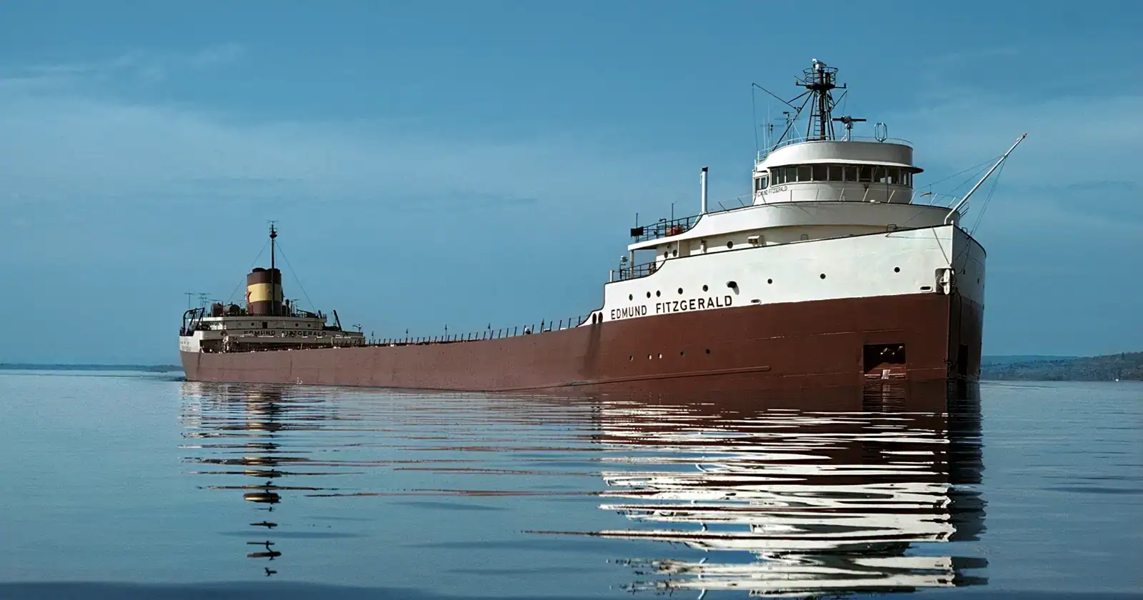 Rusty ship Edmund Fitzgerald docked at a calm lake, part of maritime history exhibits at The History Museum.