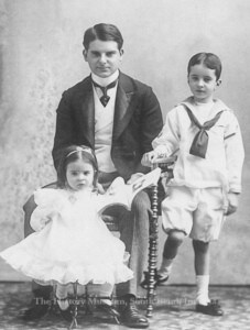 Vintage family portrait of a father and two children, highlighting early 20th-century fashion and family life at The History Museum.