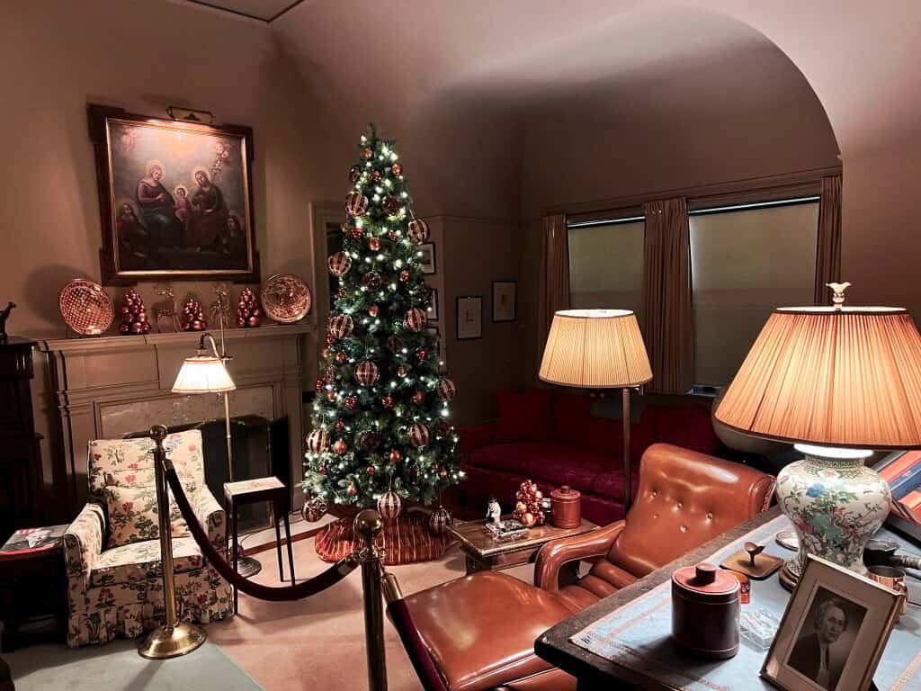 Festive living room with decorated Christmas tree, classic furniture, holiday ornaments, and warm lighting, showcasing traditional holiday decor at The History Museum.
